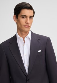 Donkerblauwe blazer van soepel materiaal, voorzien van notch revers, een enkele knoopsluiting en een witte pochet in de borstzak.