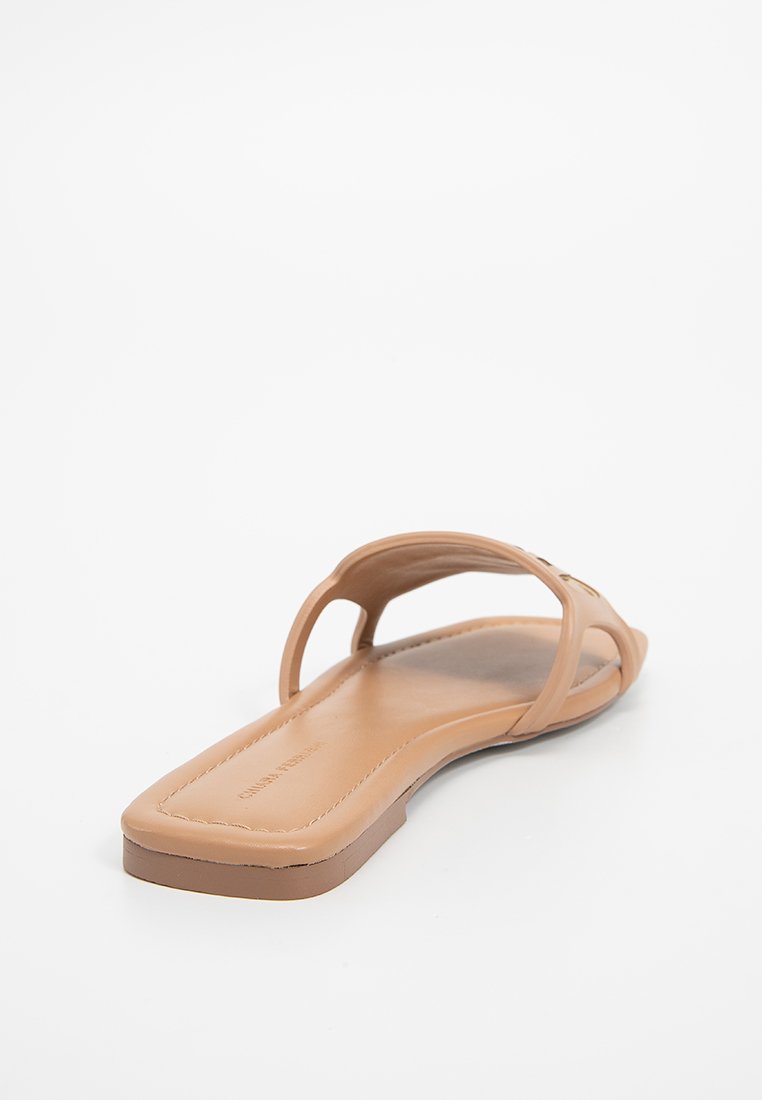 Sandale glissante tan avec deux larges sangles, semelle plate et texture lisse. Design minimaliste avec un coussin de pied confortable et sans quincaillerie visible.