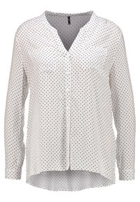 Blusa bianca a maniche lunghe con pois neri, scollatura a V, due tasche sul petto e orlo curvo. Tessuto leggero con una texture morbida.
