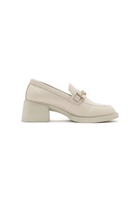 Mocasines de piel beige con tacón cuadrado, bajo tacón y detalle de hebilla dorada en la correa. Textura suave y diseño minimalista.