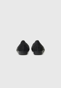 Papuci negri din suede cu un profil joas, vârf rotund, textură netedă și un design subtil. Talpa din cauciuc ușoară oferă flexibilitate.