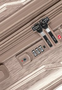 Valigia rigida in taupe metallico con finitura testurizzata, doppi zip, serratura combinata e chiave approvata dalla TSA.