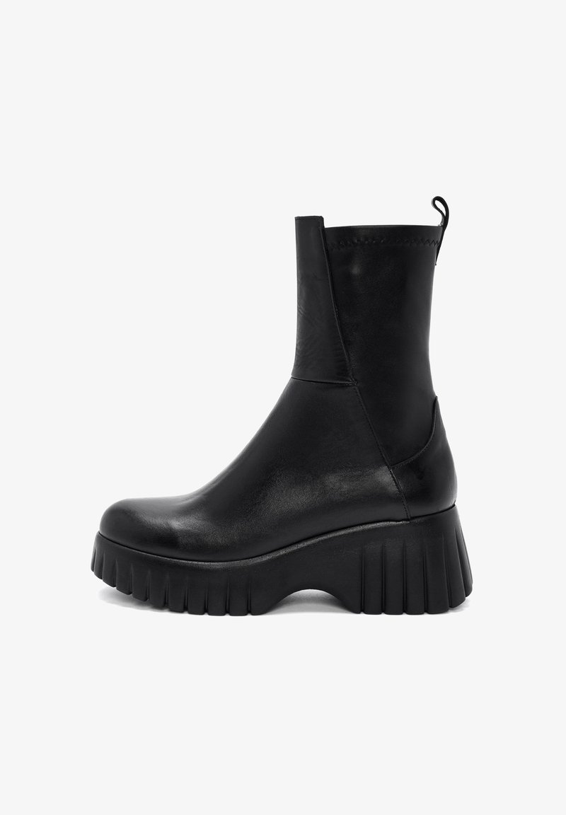 Bottines en cuir noir avec une semelle plateforme épaisse, une finition lisse et une languette à l'arrière pour un enfilage facile.