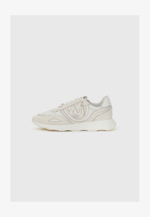 Beige sneakers med textured læder og syntetiske materialer, med et fremtrædende logo detaljer på siden og en let hvid sål.