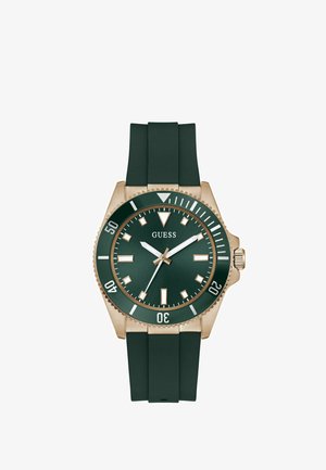 Zöld gumi szíjas óra aranyszínű tokkal, zöld számlappal és fehér mutatókkal. Forgatható lünettával és dátumkijelzővel rendelkezik.