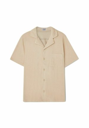 Camisa de manga corta, de color beige claro, hecha de un tejido suave; cuenta con un cuello tipo solapa, seis botones en el frente y un bolsillo en el pecho.