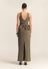 Olijfgroene maxi-jurk met een aansluitend lijfje, peplum taille, lage rug en een voorkap. Soepele textuur en minimalistisch ontwerp.