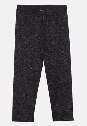 Leggings en dentelle noire avec un motif floral, taille élastique et design ajusté. Matériau léger avec une finition texturée.