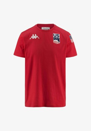 T-shirt in cotone rosso con il logo Kappa sulla spalla sinistra, un emblema statunitense sul davanti e una piccola bandiera americana sulla manica destra.