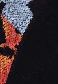 Knit fabric featuring a geometric pattern in blue, orange, and black with varying textures; the design includes sharp angles and contrasting colors.