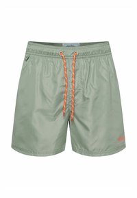 Jasnozielone kąpielówki z gładkiego materiału, posiadające elastyczny pasek w talii, pomarańczowy ściągacz oraz boczne kieszenie. Subtelne logo na dolnym brzegu.