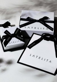 White gift boxes of varying sizes with black ribbon. "LATELITA" printed in black on each box. Simple design with clean lines and contrast.