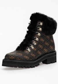 Bottine noire en fausse fourrure avec un extérieur en cuir marron à motifs, éléments en métal argenté et une semelle épaisse à crampons.