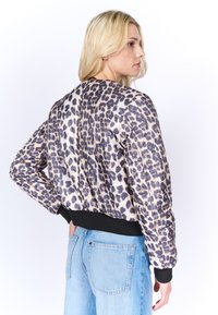 Giubbotto bomber in stampa leopardata realizzato in tessuto leggero con un design cropped e polsini a coste neri, caratterizzato da una texture liscia e da una leggera lucentezza.