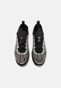 Scarpe sportive nere e grigie con pannelli in rete, lacci elastici e suola texture. Presentano linguette sul tallone per una facile calzata.