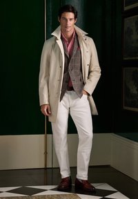 Abrigo trench beige, chaleco gris a cuadros, camiseta polo rosa, pantalones blancos, zapatos marrones. Tejido suave, corte entallado, diseño minimalista.