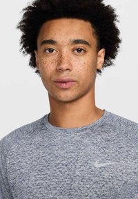 Camiseta atlética de Nike en un tejido de punto texturizado en azul marino y gris, con cuello redondo y un sutil logotipo en el lado izquierdo del pecho.
