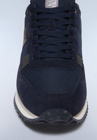 Sneaker blu navy realizzato in una combinazione di materiali scamosciati e in rete, con lacci piatti e una suola in gomma bianca e nera a contrasto.