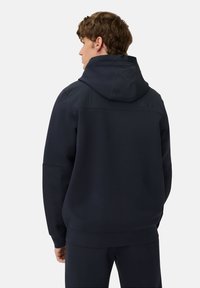 Mørkeblå hættetrøje lavet af blødt stof, med en rummelig hætte, ribbede manchetter og kant, samt et minimalistisk design uden synlige logoer.