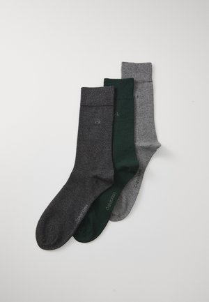Drei Paar Socken: dunkelgrau, forstgrün und hellgrau. Jede hat eine glatte Textur und einen gerippten Bund, mit Branding in der Nähe der Zehen.