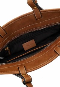 Bruine leren handtas met zichtbare witte stiksels, zwarte stofinterieur en een ritsbinnenvak met een lederen merklabel.