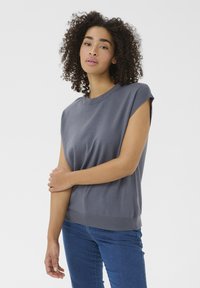Grå kortærmet strikket sweater med rund halsudskæring og ribbet kant. Bæres med blå denim jeans. Blød tekstur, afslappet pasform og minimalistisk design.