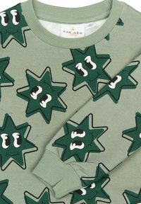 Pulover verde cu un model de stele și ochi mari, fabricat dintr-un material moale, cu manșete și guler răsucit.