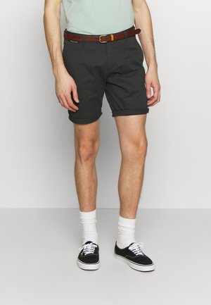 Pantaloncini grigio scuro con orli risvoltati, abbinati a calzini bianchi e sneakers nere. Una cintura marrone accentua la vita. Design semplice e casual.