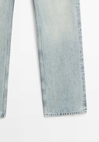 Jambes de jean en denim bleu clair présentées à plat, avec une coupe droite et des coutures visibles le long des coutures et des ourlets sur fond blanc.