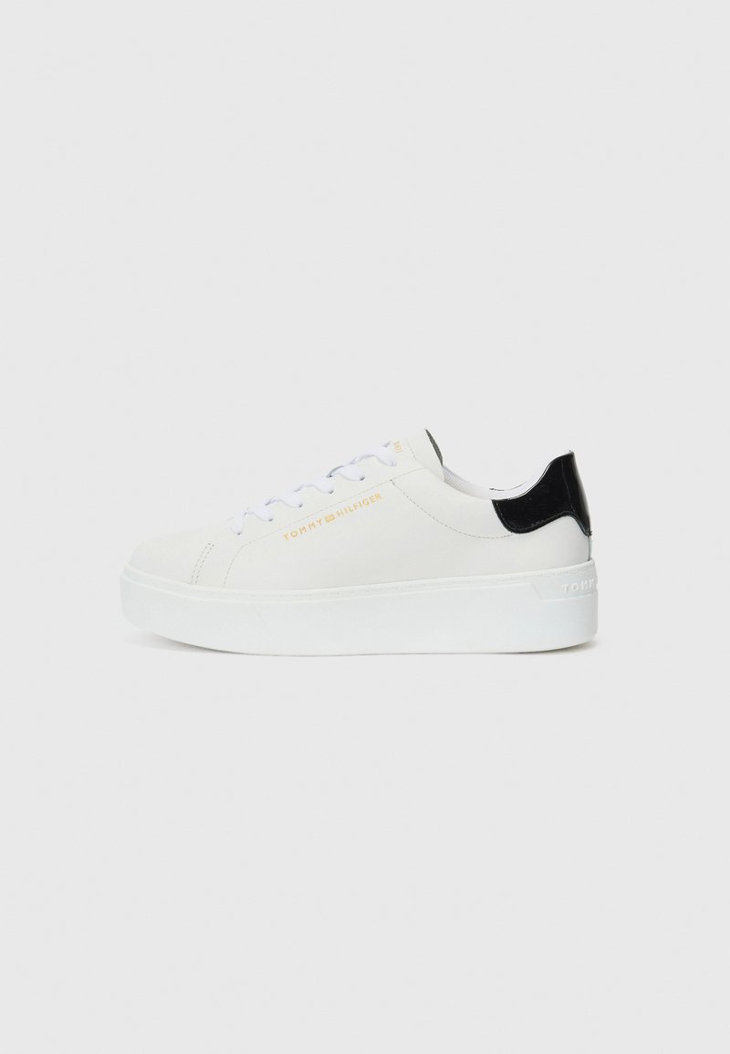 Baskets blanches avec une tige en cuir lisse, un dos en cuir verni noir, une épaisse semelle blanche et un logo de marque doré sur le côté. Design à lacets.