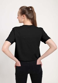 Sort kortærmet T-shirt med klassisk rund hals, glat stofstruktur og standard pasform, set fra ryggen.