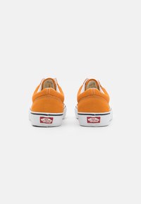 Oranžové semišové nazúvacie topánky s bielymi gumovými podrážkami, so polstrovaným golierom a logom Vans na päte. Jednoduchý, nízkoprofilový dizajn.
