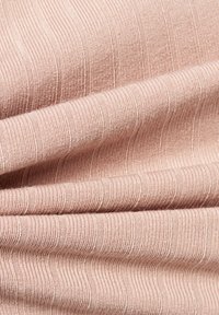 Jasnoróżowa materiał prążkowany o miękkiej teksturze, z na przemian wystającymi i płaskimi paskami, tworzącymi subtelny wzór.