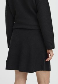 Zwart gebreid trui- en rokken set, met een zachte textuur, geribbelde manchetten en een uitlopende rok, met strakke lijnen en een minimalistisch ontwerp.