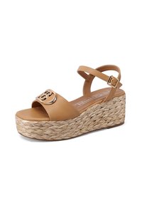 Sandali con zeppa color beige con una fascia larga che presenta un accento in metallo dorato con il logo. La suola è realizzata in materiale jute intrecciato per una maggiore texture.