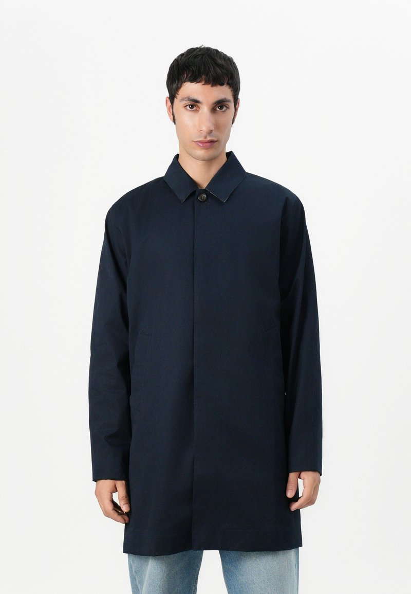 Casaco azul marinho feito de um tecido suave; possui colarinho, fecho frontal com botões e bolsos laterais; corte descontraído com mangas longas.