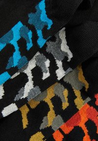 Farverige mønstrede sokker med en sort base og abstrakte designs i blå, grå, gul og orange. Fremstillet af strikket materiale.