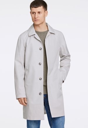 Gabardina gris claro con un diseño clásico, que cuenta con un cuello con muescas, seis botones y bolsillos laterales. Lleva puesta una sudadera texturizada.