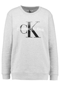 Šedá bavlněná mikina s klučičím výstřihem, dlouhými rukávy a žebrovanými manžetami. Má velké černé logo "CK" a nápis "CALVIN KLEIN JEANS".