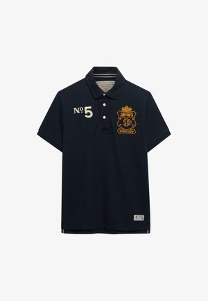 Marineblauw poloshirt van katoen, met een kraag, drie knopen en geborduurde gele details, waaronder een wapenschild en nummer 5.