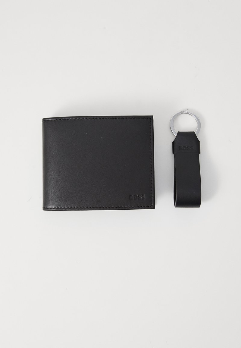 Zwart leren portemonnee met een strak design, voorzien van gestikte randen en een reliëflogo. Vergezeld van een bijpassende zwarte sleutelhanger.
