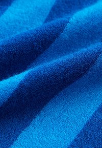 Kék csíkos textil, különböző árnyalatú kékekkel, puha, texturált felülettel, amely kiemeli a lágy, nedvszívó szálakat.