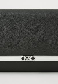 Svart teksturert clutch-veske med en sølvfarget metallaccent som har bokstavene "CMK" og linjert detaljering over midten.