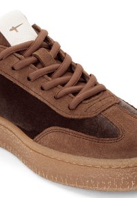 Brauner Sneaker aus Wildleder und Stoff mit passenden braunen Schnürsenkeln, Gummisohle in Kaugummi-Optik und weißem Lederzungen-Tab mit minimalistischem Logo.