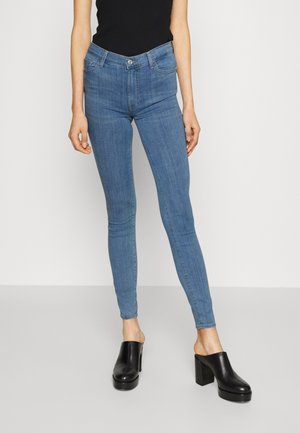 Lyseblå skinny jeans i denim, med klassisk fem-lommers design og høy midje, kombinert med svarte hæl-mules.