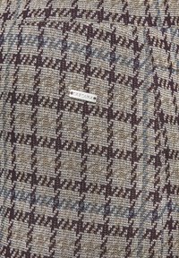 Gestructureerde stof met een houndstooth patroon in bruin, beige en blauwe tinten. Voorzien van een klein zilver label met "LASCANA" eraan bevestigd.