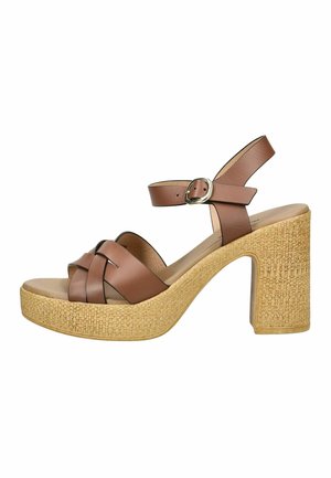 Sandalo con tacco alto in pelle marrone con suola platform intrecciata e cinturino alla caviglia con fibbia argentata, mostrato su sfondo bianco.