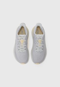 Light gray athletic shoes with a textured upper, yellow accents, flat laces, and a cushioned sole. Features a streamlined design.