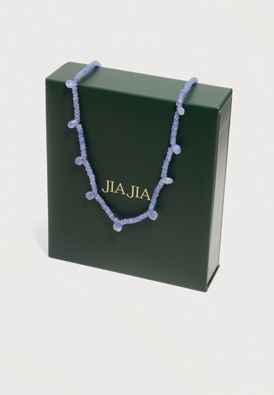 Κολιέ με χάντρες λεβάντας σε σχήμα σταγόνας, τοποθετημένο πάνω σε σκούρο πράσινο κουτί με χρυσά γράμματα "JIA JIA".
