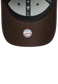 Gorra de béisbol marrón con estructura rígida, visera negra y una pegatina circular de la MLB con una pelota de béisbol en la parte frontal. El interior tiene una tela clara.